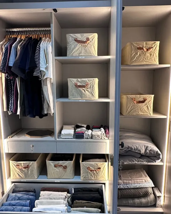 This beautifully lit wardrobe shows a perfect balance of hanging space for shirts and folded items in drawers and matching bins. Creating this functional harmony is key to a closet that works for you, not against you.