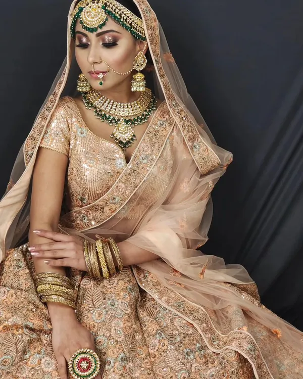 This is the kind of stunning, professional shot we aim for. A model in a beautiful peach sequin lehenga, complete with matching jewellery, against a clean studio backdrop that makes the entire look pop.