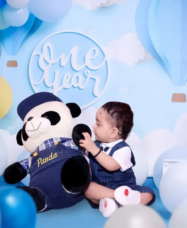 A classic 'One Year' milestone photoshoot with a blue and white theme, complete with a large number '1' prop and a friendly panda.