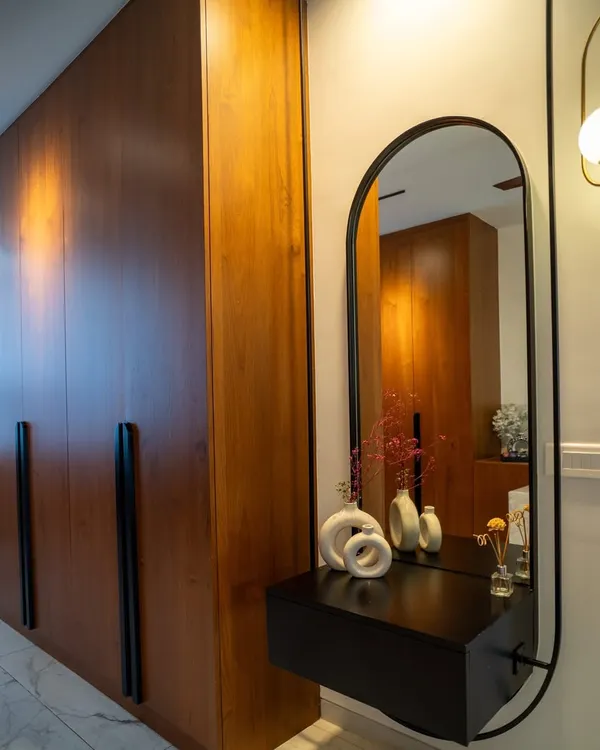 A close-up of a veneer-finished wardrobe with long, statement black handles, paired with a custom-designed floating dressing console.