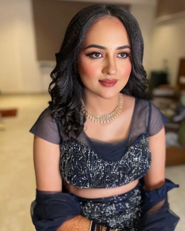 An elegant and modern reception look featuring a navy blue lehenga. The makeup is soft and glamorous with a neutral lip, paired with crimped waves for a chic hairstyle.