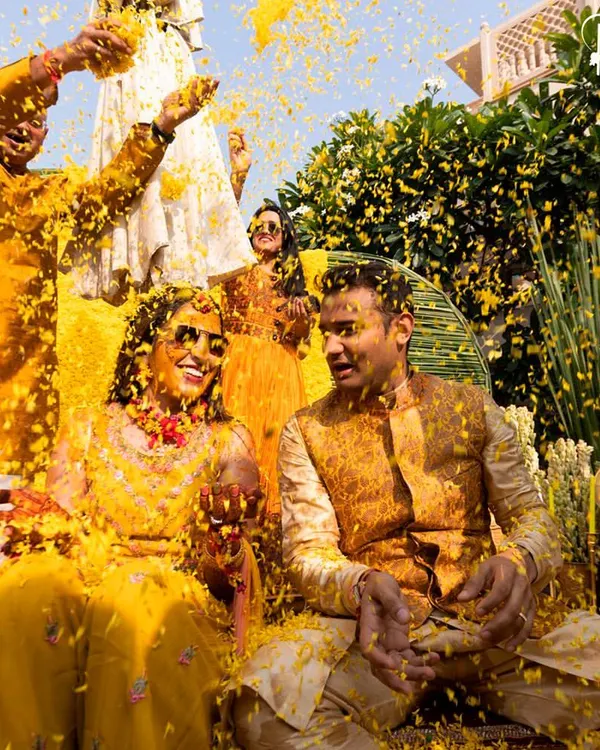 The peak of a joyous Haldi ceremony, where the couple is showered in a rain of bright yellow marigold petals. I designed the entire setup in monochrome yellow to make this vibrant moment pop.