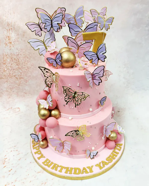 This two-tiered Pink Cake With Butterflies is a whimsical dream, with a cascade of lilac and gold butterflies fluttering around the soft pink tiers.