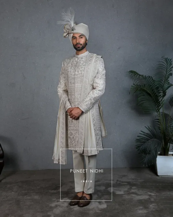 This handcrafted ivory sherwani is the embodiment of regal grace, designed for your most precious day. The intricate Resham and zari embroidery, inspired by Mughal architecture, flows across the silk fabric, creating a timeless heirloom.