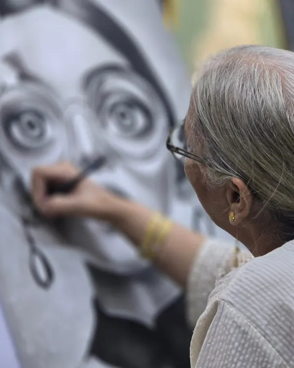 An artist at work. This image captures the intense focus required for charcoal portraiture as a student adds finishing touches to the eye, bringing the character to life.