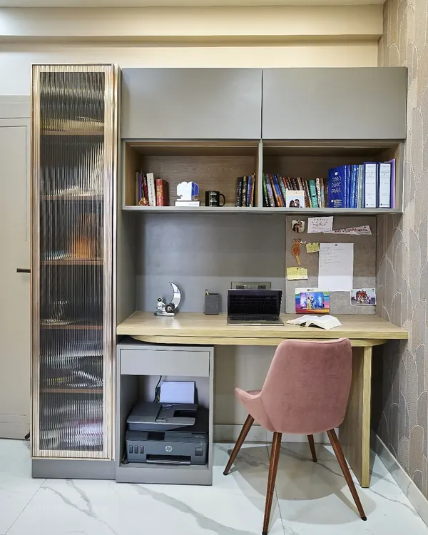 A compact and efficient study nook. The design includes open shelves for books, a corkboard for notes, and a drawer for stationery. The fluted glass cabinet on the side adds a stylish touch while providing concealed storage.