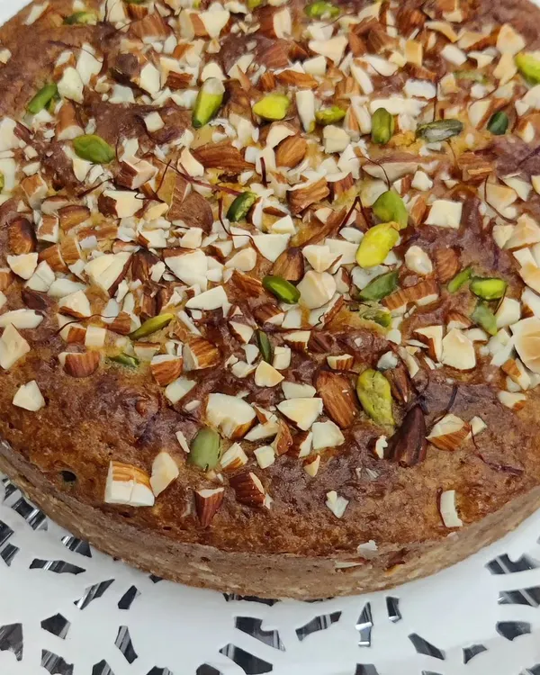 Our homemade and eggless Saffron Almond Tea Cake, generously topped with sliced almonds and pistachios, perfect for birthdays or any celebration.