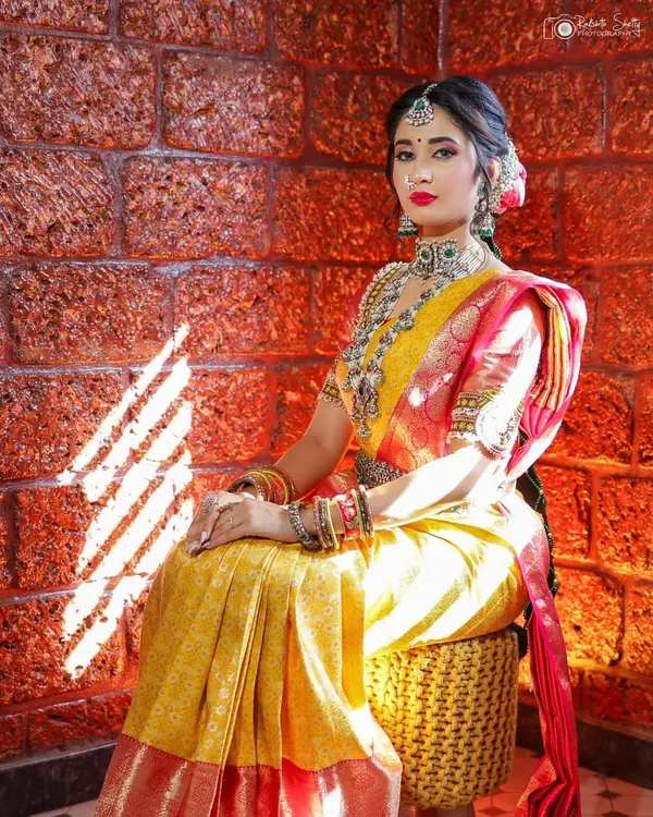A beautiful bridal portrait session. The warm light hitting the laterite brick wall complements the yellow and red silk saree, creating a rich and timeless image.