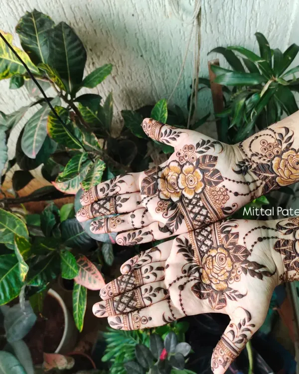 This stunning floral design features large, shaded roses on the back of the hands. The use of bold lines and delicate beaded chains creates a beautiful contrast.