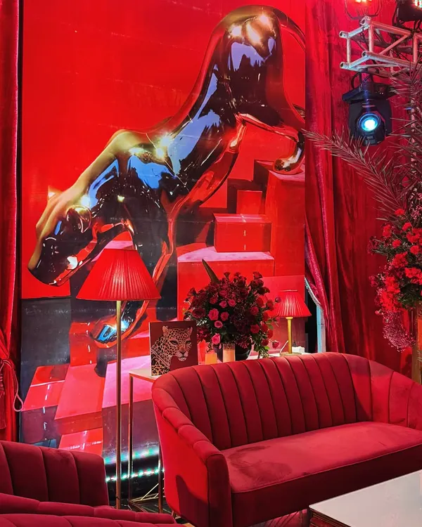 For a luxury brand activation, I drenched the space in a fiery, unapologetic red. This setting, with its plush velvet sofa and a metallic panther poised against a dramatic backdrop, isn't just a room; it's an arrival.