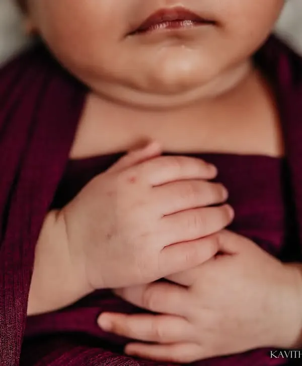 A macro shot of a newborn's tiny, clasped hands while swaddled in a deep purple wrap. These are the details that change so quickly, and I love preserving them.
