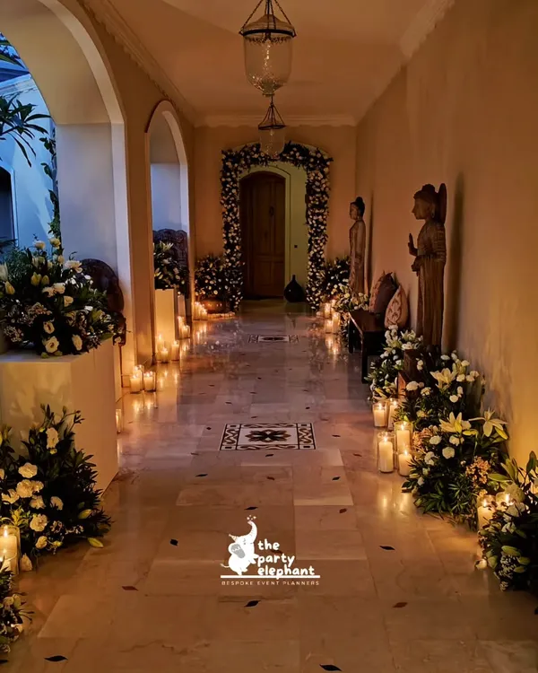 For this intimate wedding, I created a romantic candlelit hallway to welcome guests. The path was lined with large pillar candles and lush arrangements of white flowers, leading to a beautifully decorated floral archway.