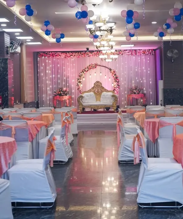 A wide-angle shot of a beautifully decorated wedding hall, showing the stage, seating arrangement, and balloon decorations before the guests arrive.