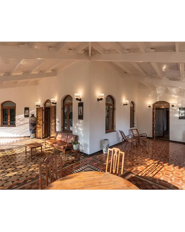 A wide view of the main hall in our Lonavala restoration project, where we balanced the structure's colonial and Indo-Saracenic influences with restored antique furniture and contemporary lighting to create a harmonious living space.