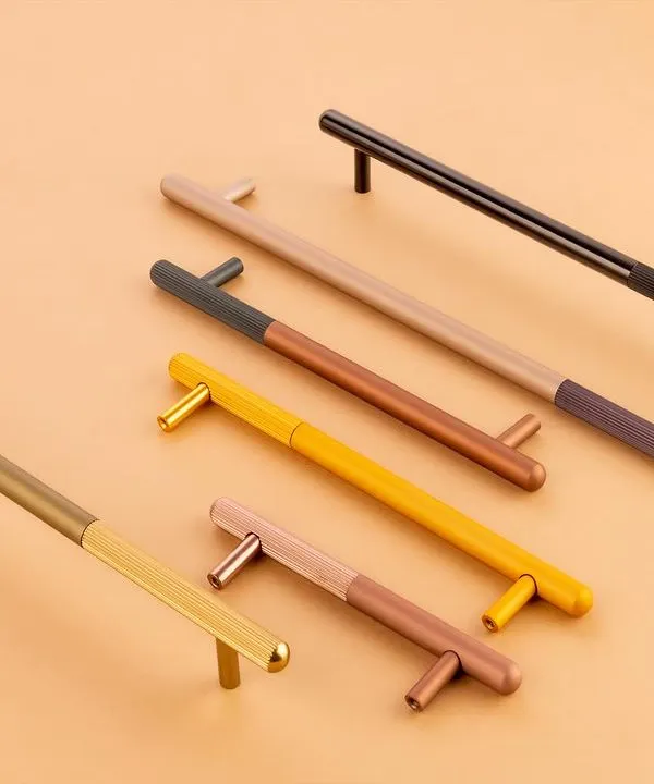 A collection of modern, dual-tone cabinet handles for Gauri Enterprises. The clean, flat-lay composition on a neutral background highlights their sleek design and color variations.