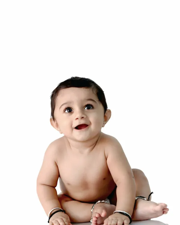 A simple and beautiful portrait of a happy baby sitting against a clean white background, with a joyful and innocent expression.