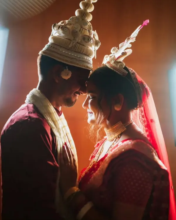 An intimate, beautifully lit portrait of a Bengali bride and groom in their traditional 'topor' and 'mukut'.