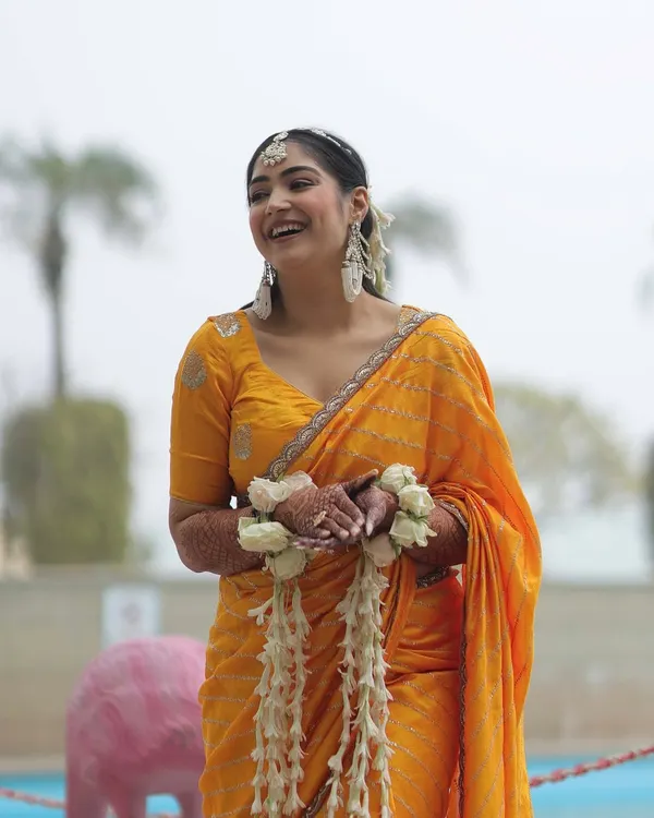 A candid laugh during my Haldi. I chose a simple, lightweight yellow saree so I could be comfortable and enjoy the day. The look was completed with fresh floral bracelets and statement earrings.