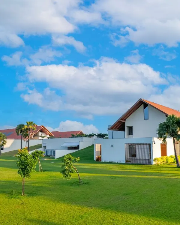 The campus of Vellore International School in Chennai, with its distinctive sloping tiled roofs and buildings set within a vast green landscape. The design creates a human-scaled, unintimidating environment for young students.
