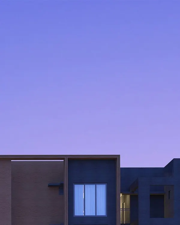 An abstract view of a building at twilight, where the simple geometry of the structure is silhouetted against a deep purple sky, creating a moment of quiet beauty.