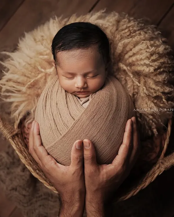 "Of all the things my hands have held, the best by far is you." This portrait, with the baby nestled in a basket and held by loving hands, symbolizes safety, warmth, and parental love.