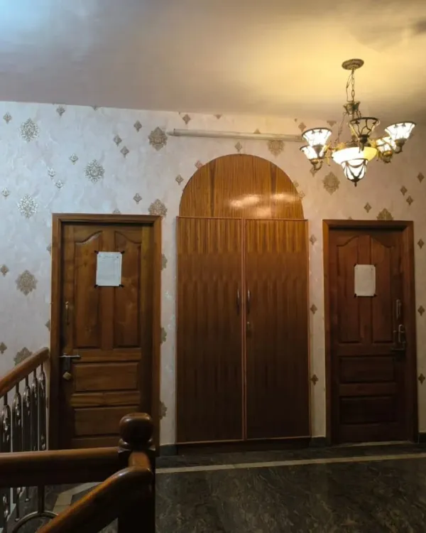 An elegant, light-colored damask wallpaper with a subtle gold motif, installed in a hallway and staircase area.