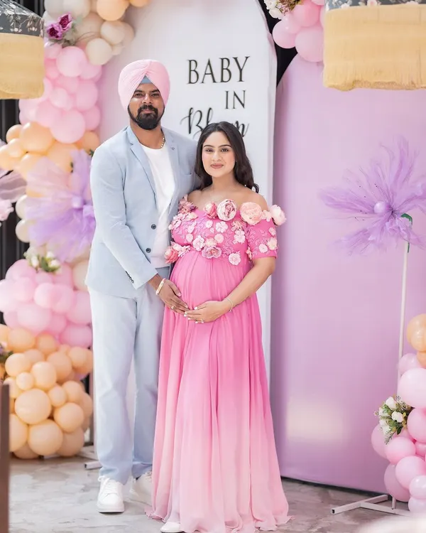 A beautiful portrait of the happy couple at their "Baby in Bloom" themed baby shower. Their coordinated outfits and the stunning balloon decor create a perfect memory of this special celebration.
