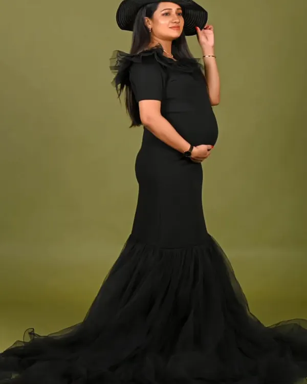 Sleek and sophisticated, this black mermaid gown features a fitted silhouette that flares into a dramatic tulle train. The look is completed with a stylish hat for a touch of classic glamour.