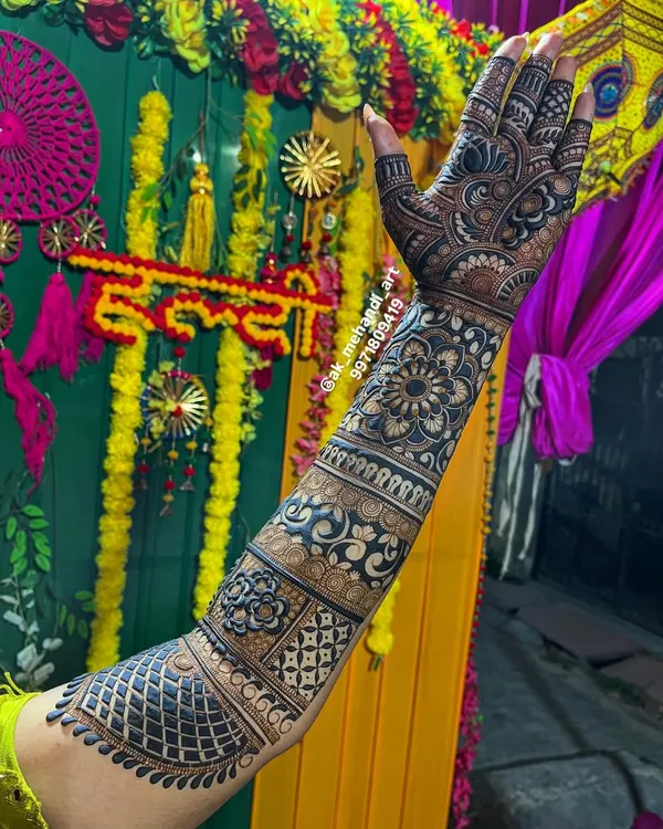 A full bridal arm design against a vibrant Haldi ceremony backdrop. I combine various patterns like jaal, paisleys, and floral bands to create a rich and cohesive look that extends up the arm.