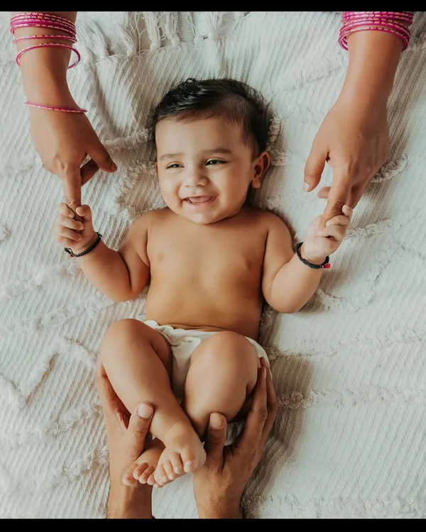 There is nothing more beautiful than a baby's smile. This moment, with mom and dad's hands holding their little one, captures the pure joy and connection that fills a new family. These are the simple, heartfelt memories I aim to preserve for you.