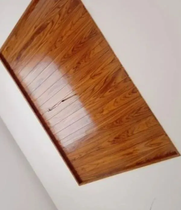 A high-gloss wood polish on this ceiling panel brings out the rich texture and grain of the wood, creating a reflective, premium finish for the entire room.