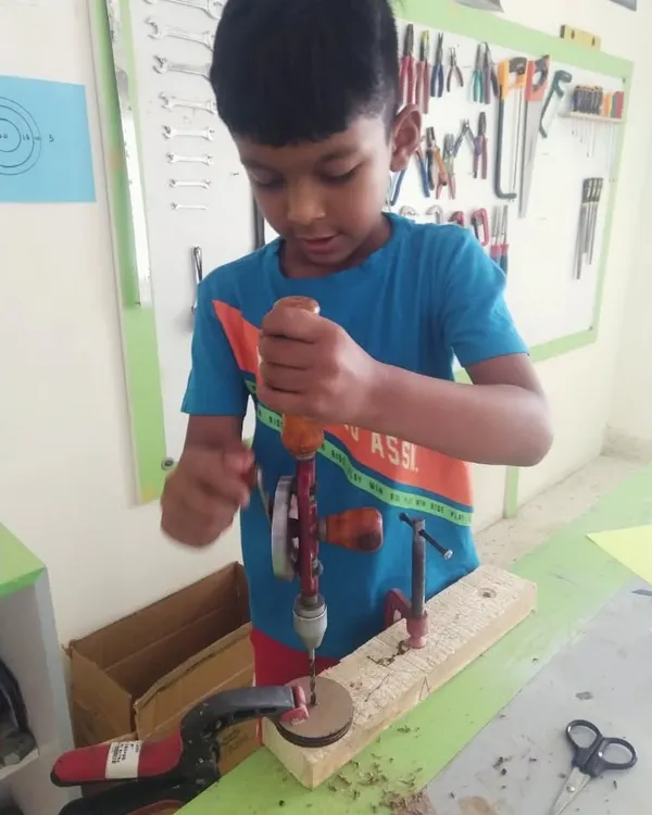 Using a hand drill requires focus and two hands. We teach kids the proper technique, ensuring they are safe and successful as they drill holes for their projects.