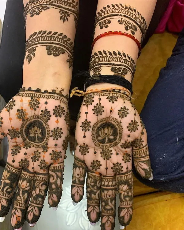A balanced and symmetrical design featuring a lotus mandala on the palm. This style of intricate henna art provides full coverage while maintaining a feeling of elegance and order.