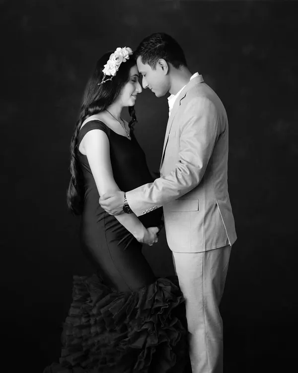A tender black and white portrait of an expecting couple. The focus is entirely on their connection as they touch foreheads, creating a quiet, intimate, and timeless image.