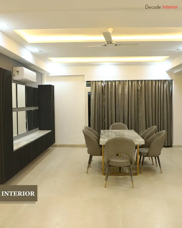 This dining area is designed for memorable gatherings. It features a marble-top dining table, comfortable upholstered chairs, and a custom-built crockery unit with a mix of open and closed storage.
