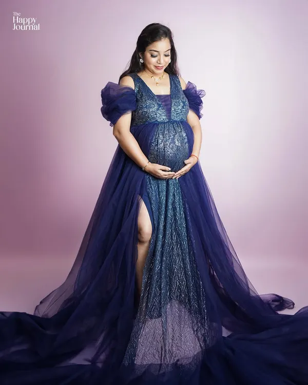 A moment of pure glamour. This expectant mother looks radiant in a sparkling blue gown with a dramatic train, showcasing the high-fashion style we can achieve in your maternity session.