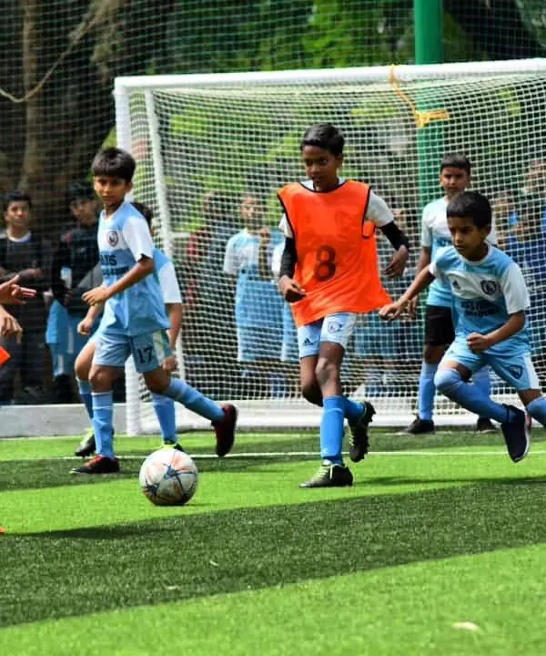 A fantastic action shot from one of our youth tournaments. A player in an orange bib skillfully maneuvers the ball, surrounded by teammates, showcasing the dynamic gameplay we foster.