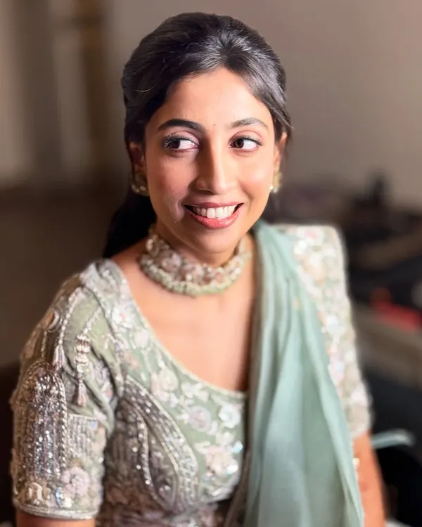 A candid, happy shot of my bride Neha at her reception. Her minimal glam makeup features a soft pink eyeshadow and a radiant base that glows under the lights, perfectly matching her pastel green lehenga.