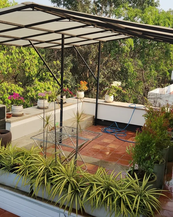 We turned this HSR Layout terrace into a serene escape. This complete balcony makeover features a custom pergola for shade, a variety of flowering and foliage plants in decorative pots, and a comfortable seating area, demonstrating how we maximize greenery in urban homes.
