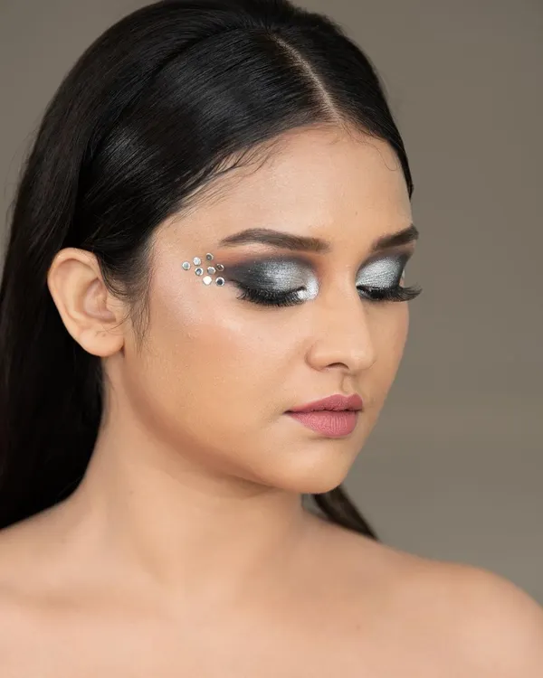 A close-up beauty shot showcasing a dramatic silver eye makeup look with crystal embellishments. This type of detailed work is ideal for makeup artists' portfolios and cosmetic campaigns.