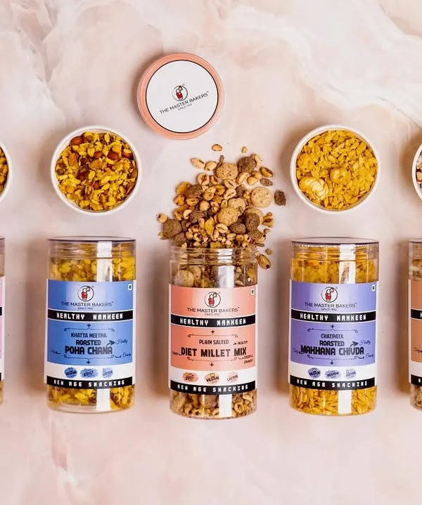 Our healthy namkeen range is your perfect snack partner. This vibrant flat lay shows our variety, including roasted Diet Millet Mix, Poha Chivda, and Sweet Puff Mix, all light, nutritious, and irresistibly tasty.