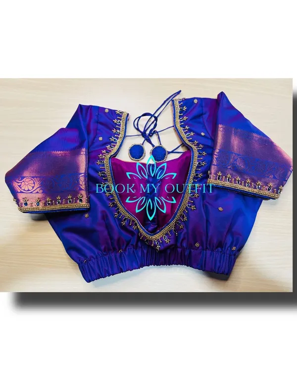 This custom-stitched blouse shows a unique cutout back design with elegant tie-ups and pom-poms. The gold zari border adds a traditional touch, and I ensure the fit is flawless for a comfortable and stylish look.