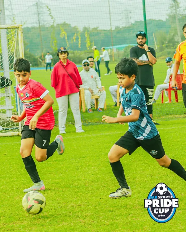 Two young players from opposing teams challenge for the ball during a fast-paced Pride Cup match, demonstrating focus and competitive spirit.