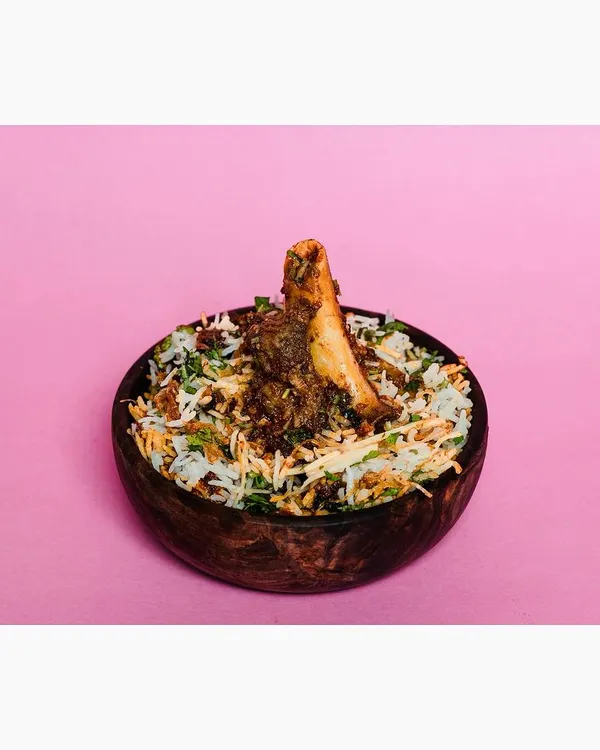 A bowl of mutton biryani shot against a vibrant, solid pink background. This modern, high-contrast style is designed to grab attention on crowded food delivery apps.