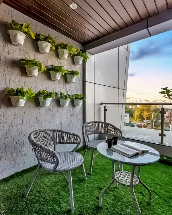 A simple yet charming balcony makeover featuring comfortable wicker chairs and an artificial grass floor. The wall-mounted planters create a vertical garden, adding life and color without taking up precious floor space.