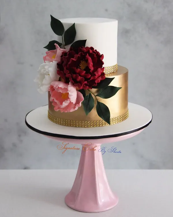 A classic and signature design of mine, this white and gold two-tiered cake is adorned with handmade sugar flowers. It's a timeless choice for an elegant engagement or wedding celebration.