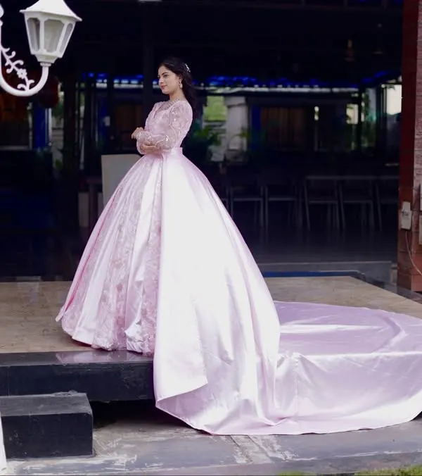 A full view of this magnificent pink ball gown, showcasing its impressive trail. This gown is crafted from lustrous satin with delicate embroidery, ensuring a grand and dramatic entrance for any bride at her reception.