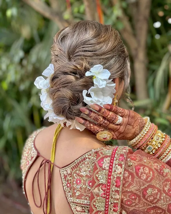 A detailed shot of a classic bridal updo, featuring a textured bun adorned with beautiful white flowers.