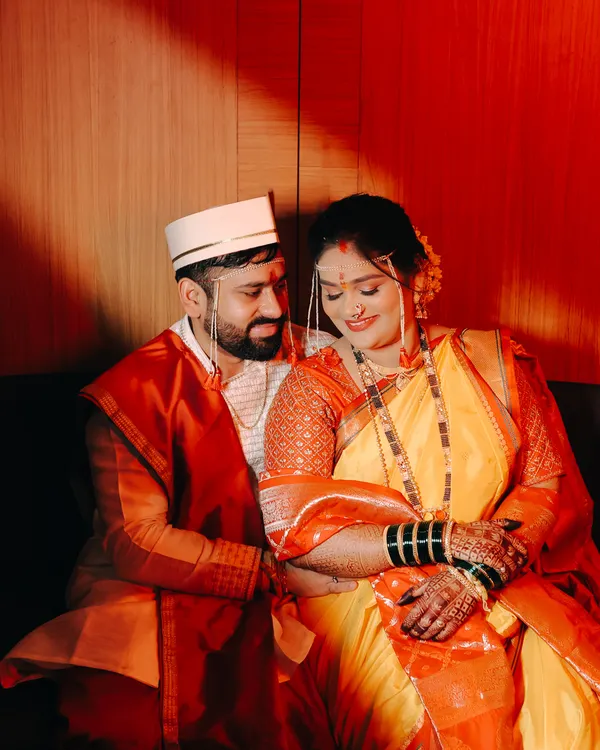 An intimate portrait of a Maharashtrian couple on their wedding day. The warm, dramatic lighting highlights their traditional attire and the quiet connection between them.