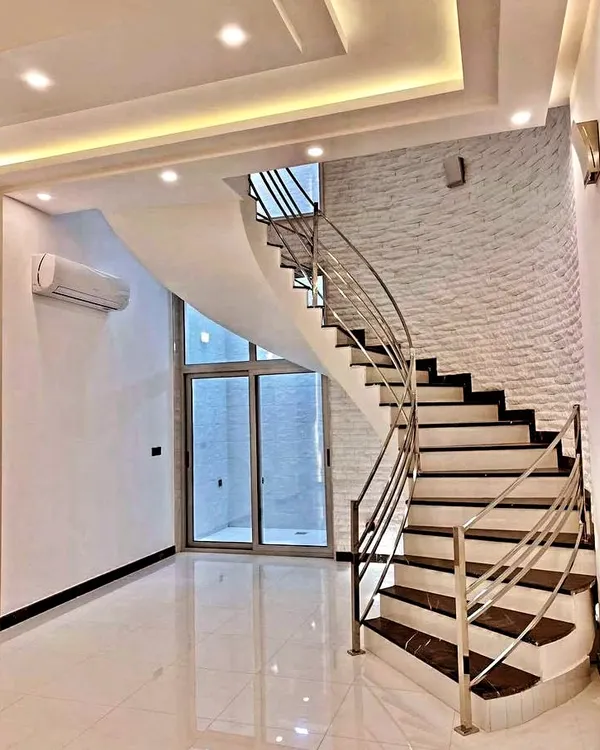 While I specialize in ceilings, my interior work often extends to other areas. This image shows a beautifully designed modern home with a stylish curved staircase that complements the overall aesthetic.